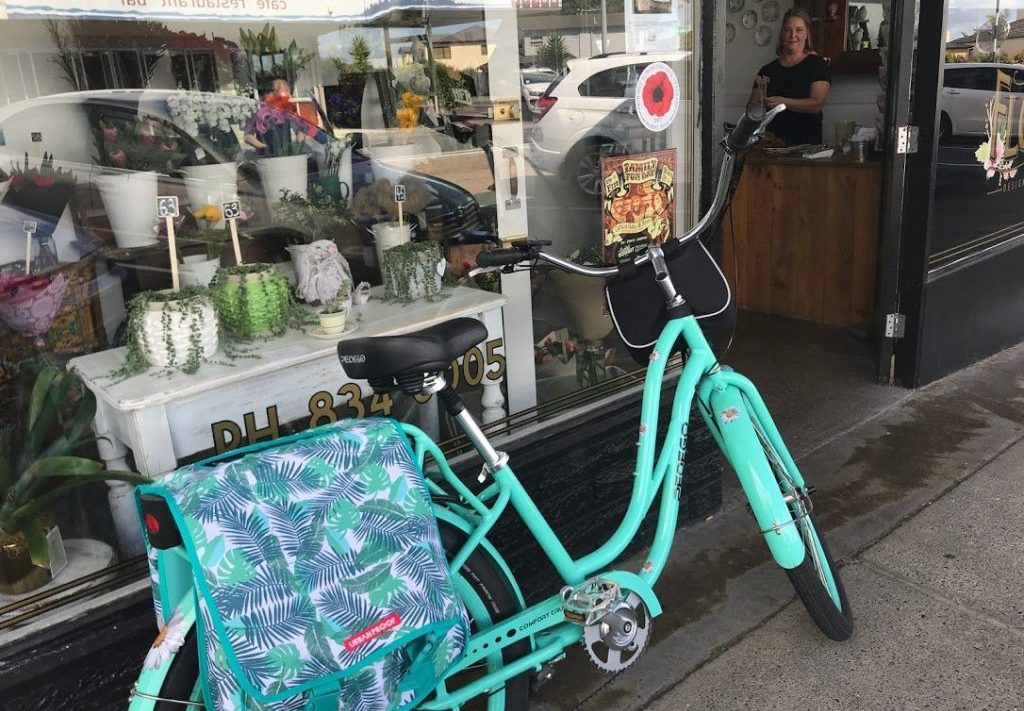 A mint green bicycle in front of a flower shop